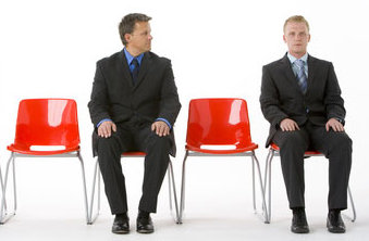 Three business people sitting on red plastic seats