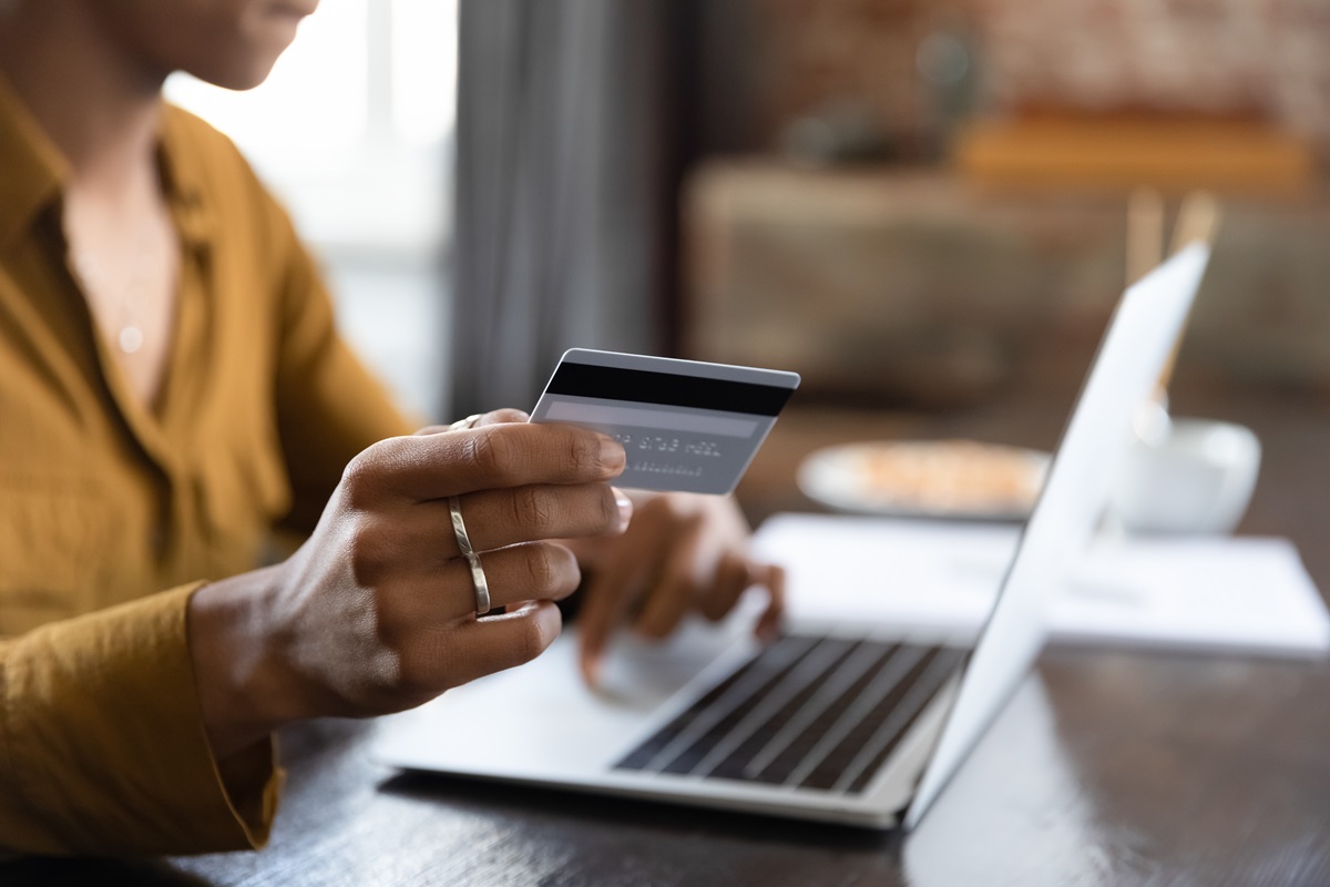 Female hand holding credit card at laptop close up