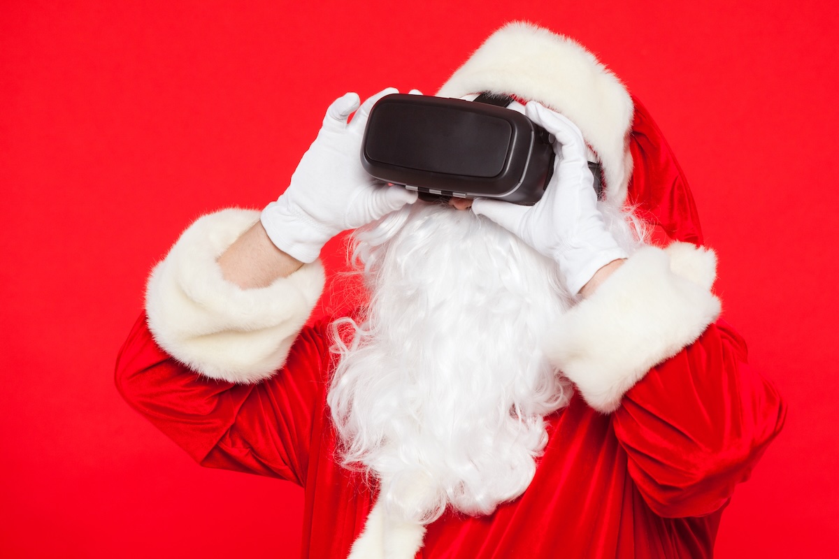 Santa Claus wearing virtual reality goggles, on a red background. Christmas