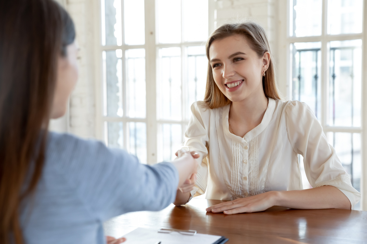 Female job candidate and employer handshake at meeting