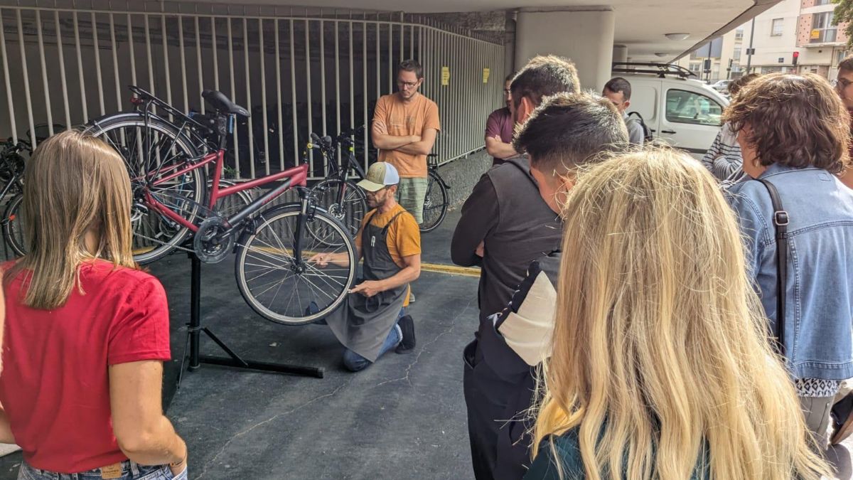 Les salariés d'Hellowork assistent à un atelier de réparation de vélo sur le parking de leur entreprise.