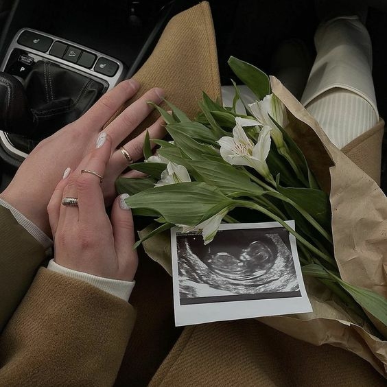 Photo de 2 personnes avec un bouquet de fleur et une échographie